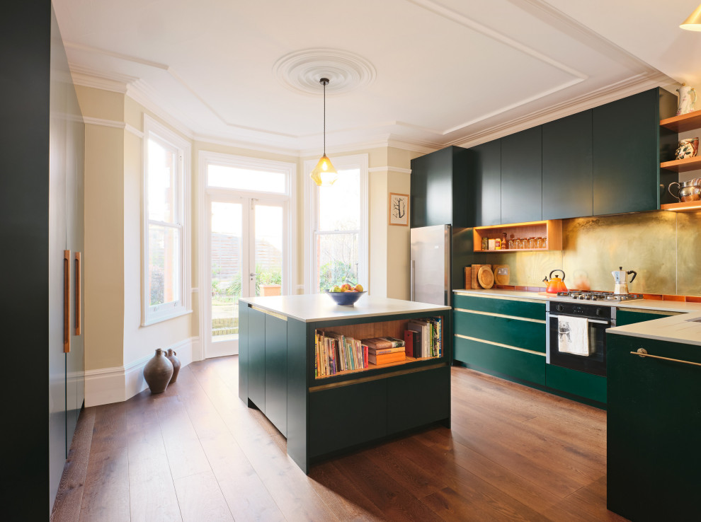 Идея дизайна: угловая кухня среднего размера в современном стиле с плоскими фасадами, зелеными фасадами, фартуком цвета металлик, островом и белой столешницей