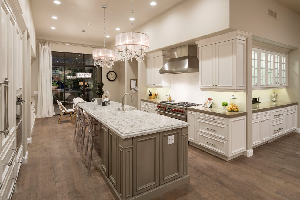 Large transitional galley medium tone wood floor and brown floor open concept kitchen photo in Phoenix with a farmhouse sink, beaded inset cabinets, white cabinets, granite countertops, stainless steel appliances and an island