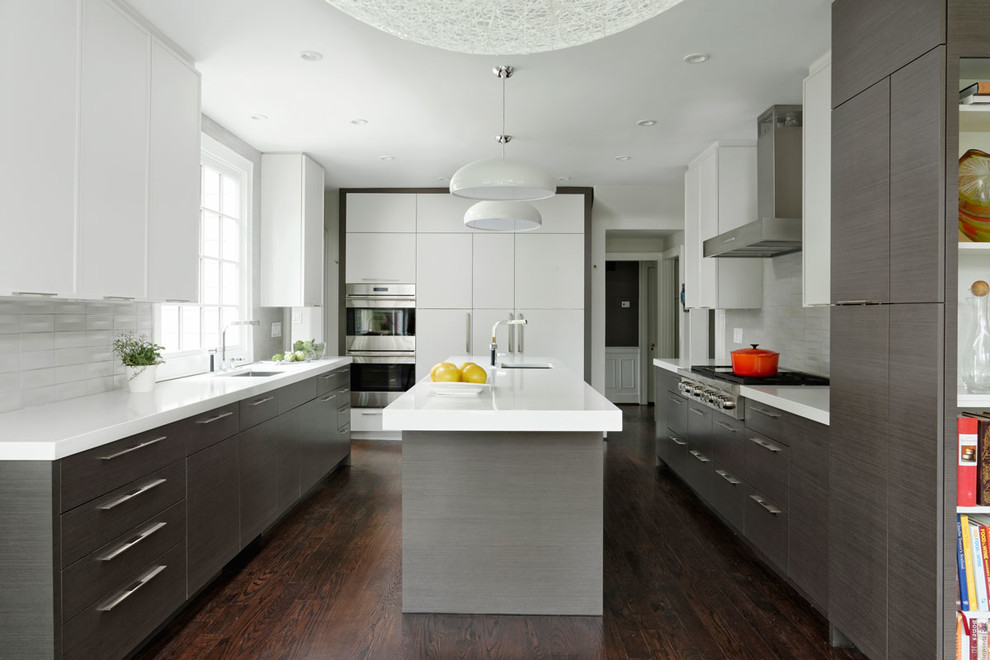 Large midcentury galley eat-in kitchen in DC Metro with a drop-in sink, flat-panel cabinets, grey cabinets, quartz benchtops, white splashback, ceramic splashback, stainless steel appliances, dark hardwood floors, with island and brown floor.