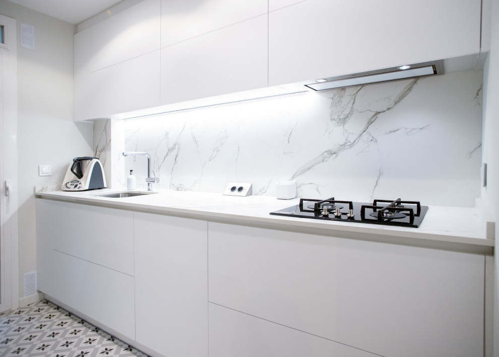 Design ideas for a large contemporary single-wall open plan kitchen in Barcelona with a single-bowl sink, flat-panel cabinets, white cabinets, marble benchtops, white splashback, marble splashback, stainless steel appliances, ceramic floors, with island, beige floor and white benchtop.