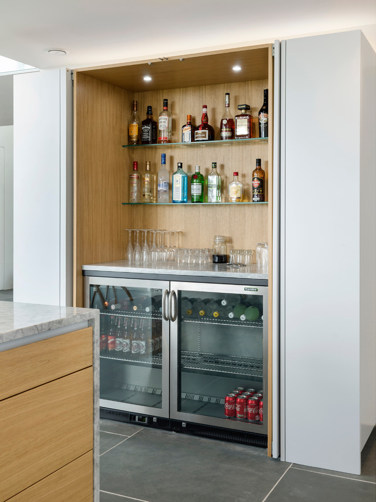 This is an example of a mid-sized contemporary wet bar in Cornwall with flat-panel cabinets, white cabinets, slate floors and grey floor.