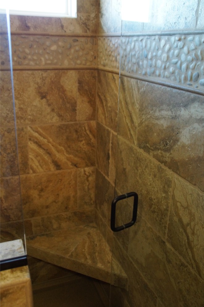 Mid-sized mountain style master multicolored tile and stone tile travertine floor alcove shower photo with raised-panel cabinets, medium tone wood cabinets, a one-piece toilet, beige walls, an undermount sink and granite countertops