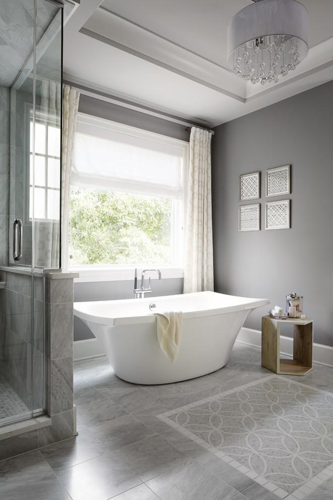 This is an example of a mid-sized transitional master bathroom in Chicago with a freestanding tub, grey walls, gray tile, mosaic tile and marble floors.