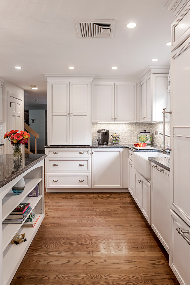Photo of a traditional kitchen in Boston with a farmhouse sink, recessed-panel cabinets, white cabinets, grey splashback and panelled appliances.
