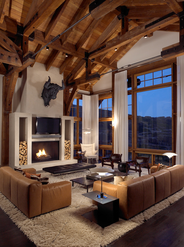 Design ideas for a large country formal open concept living room in Other with white walls, dark hardwood floors, a standard fireplace, a plaster fireplace surround, a wall-mounted tv and brown floor.