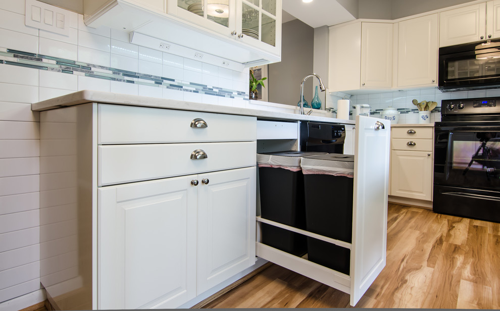 Inspiration for a mid-sized transitional l-shaped vinyl floor enclosed kitchen remodel in DC Metro with an undermount sink, shaker cabinets, quartz countertops, white backsplash, ceramic backsplash, black appliances and no island