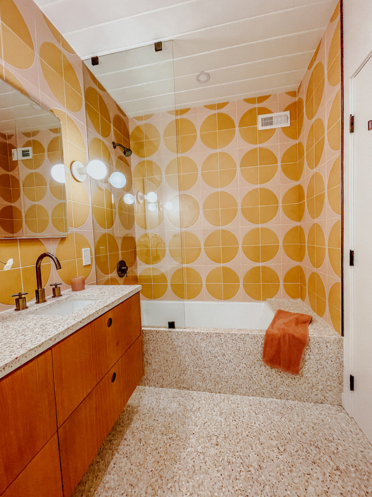 Foto på ett mellanstort 60 tals badrum, med en dusch/badkar-kombination, gul kakel, keramikplattor och flerfärgade väggar