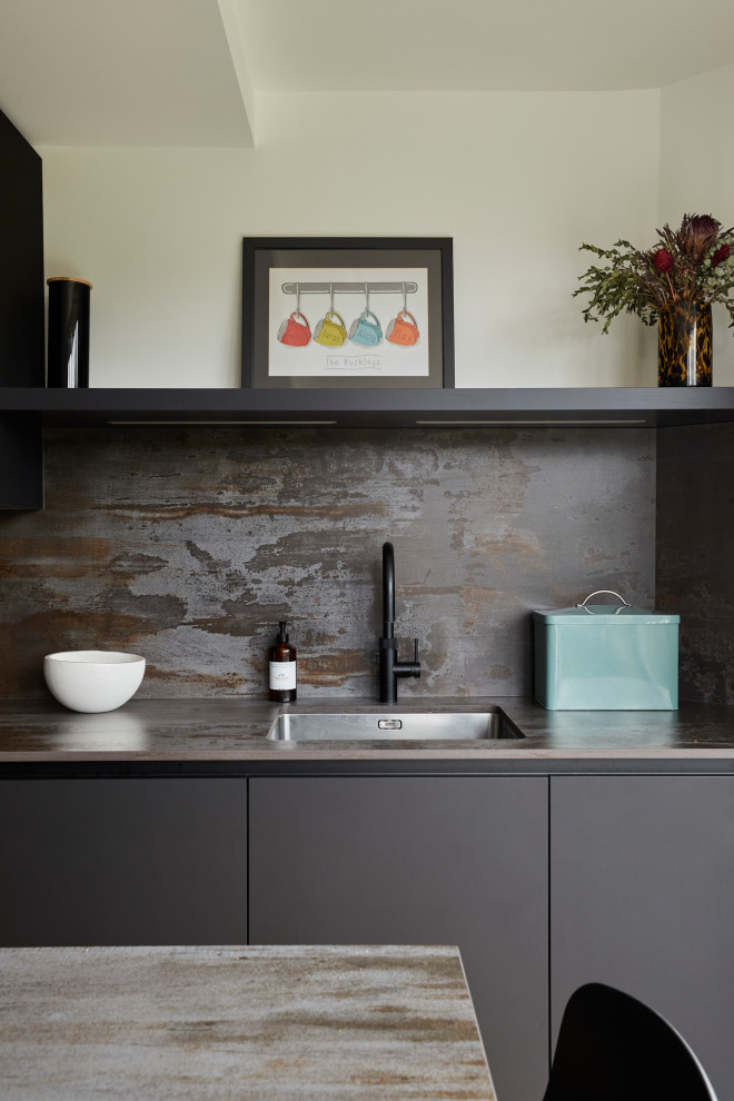 Modern inredning av ett avskilt, litet flerfärgad flerfärgat l-kök, med en undermonterad diskho, släta luckor, bänkskiva i kvarts, flerfärgad stänkskydd, svarta vitvaror, ljust trägolv och en köksö