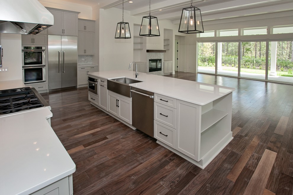 Inspiration for a large transitional open plan kitchen in Atlanta with a farmhouse sink, shaker cabinets, grey cabinets, quartz benchtops, stainless steel appliances, medium hardwood floors and multiple islands.