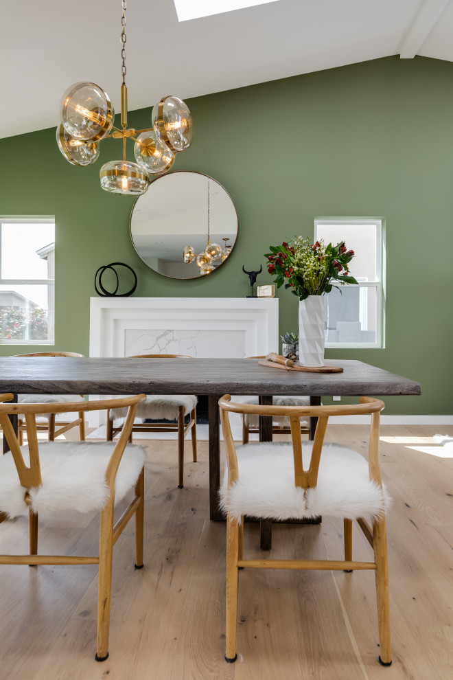 Foto di una grande sala da pranzo aperta verso la cucina chic con pareti verdi, parquet chiaro, camino classico, cornice del camino in legno e soffitto a volta