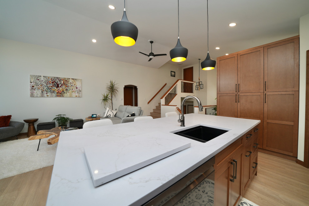 Eat-in kitchen - l-shaped vinyl floor and beige floor eat-in kitchen idea with a single-bowl sink, shaker cabinets, brown cabinets, quartz countertops, white backsplash, ceramic backsplash, black appliances, an island and white countertops