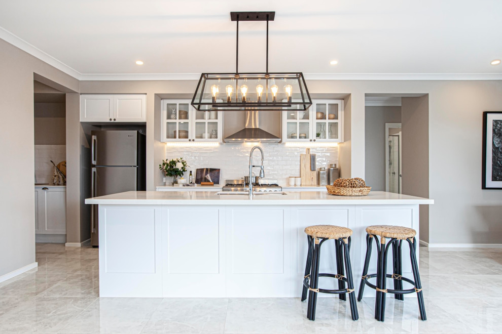 Large beach style galley kitchen pantry in Melbourne with a single-bowl sink, white cabinets, quartz benchtops, white splashback, ceramic splashback, stainless steel appliances, ceramic floors, with island, beige floor and white benchtop.