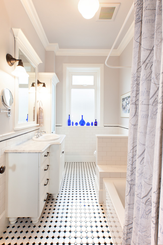Mid-sized traditional master bathroom in Vancouver with a drop-in sink, furniture-like cabinets, white cabinets, marble benchtops, a drop-in tub, a shower/bathtub combo, a one-piece toilet, white tile, ceramic tile, grey walls and mosaic tile floors.