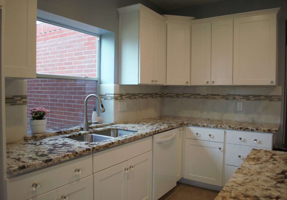 Enclosed kitchen - mid-sized transitional u-shaped terra-cotta tile and beige floor enclosed kitchen idea in Houston with a double-bowl sink, shaker cabinets, white cabinets, granite countertops, beige backsplash, stone tile backsplash, white appliances and an island