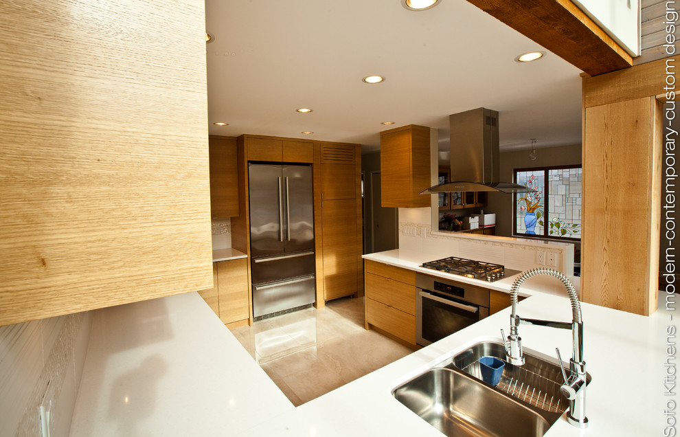 This is an example of a mid-sized contemporary u-shaped separate kitchen in Vancouver with an undermount sink, flat-panel cabinets, light wood cabinets, quartzite benchtops, white splashback, stainless steel appliances and marble floors.
