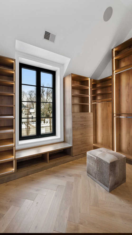 Mid-sized modern gender-neutral walk-in wardrobe in Chicago with open cabinets, medium wood cabinets, light hardwood floors, beige floor and vaulted.