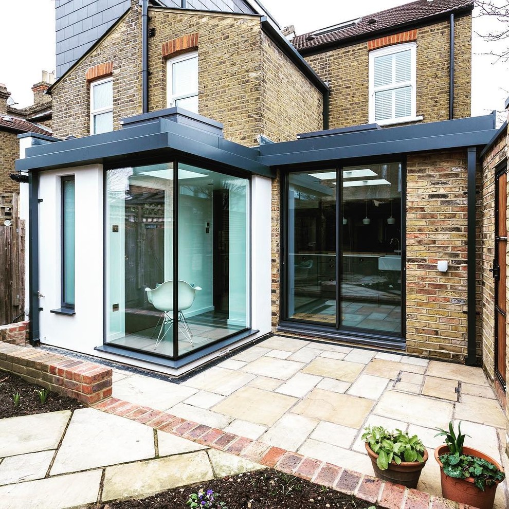 This is an example of a small contemporary two-storey brick multi-coloured duplex exterior in London with a flat roof and a mixed roof.