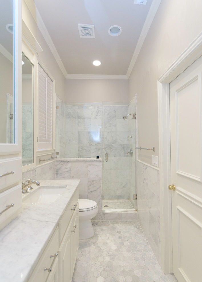 This is an example of a small contemporary bathroom in Dallas with white cabinets, an alcove shower, a one-piece toilet, grey walls, ceramic floors, raised-panel cabinets, an undermount sink, marble benchtops, gray tile, marble, grey floor and a hinged shower door.