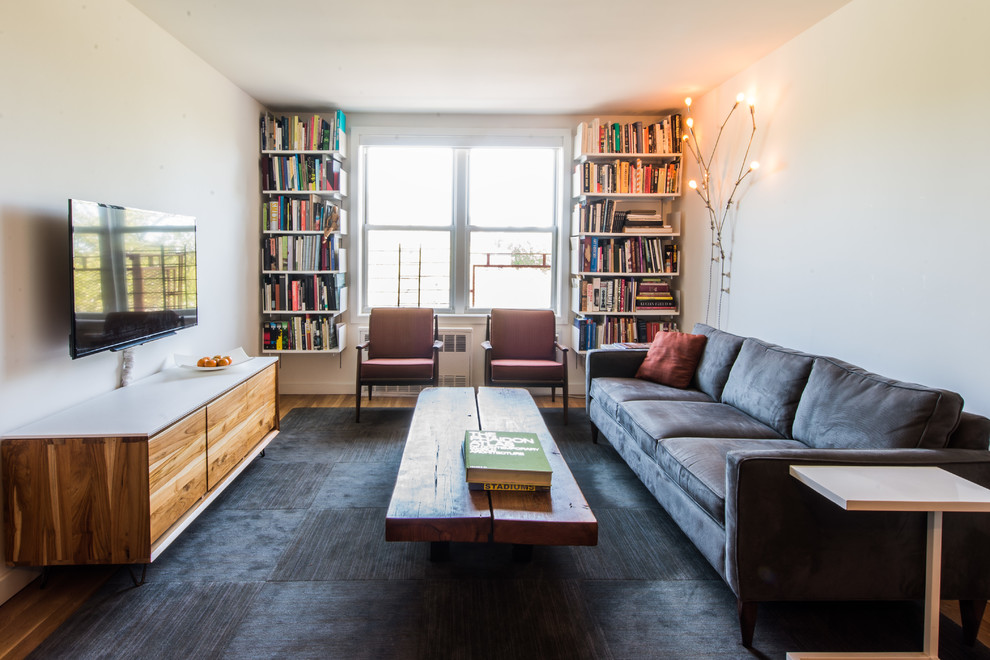 Living room library - mid-sized contemporary enclosed medium tone wood floor living room library idea in New York with white walls, a wall-mounted tv and no fireplace