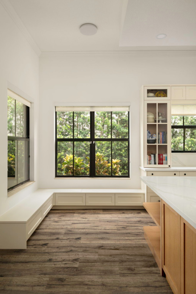 Eat-in kitchen - mid-sized transitional l-shaped laminate floor and brown floor eat-in kitchen idea in Miami with a drop-in sink, shaker cabinets, medium tone wood cabinets, quartz countertops, white backsplash, quartz backsplash, stainless steel appliances, an island and white countertops