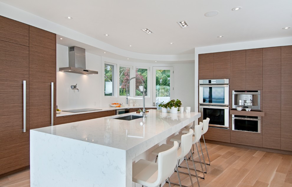 This is an example of a large contemporary l-shaped eat-in kitchen in Vancouver with an undermount sink, flat-panel cabinets, medium wood cabinets, quartz benchtops, white splashback, stone slab splashback, panelled appliances, light hardwood floors and with island.