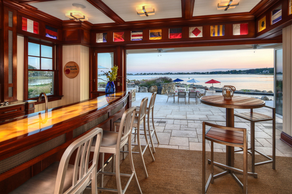 Seated home bar - mid-sized coastal galley limestone floor seated home bar idea in New York with raised-panel cabinets, dark wood cabinets and wood countertops
