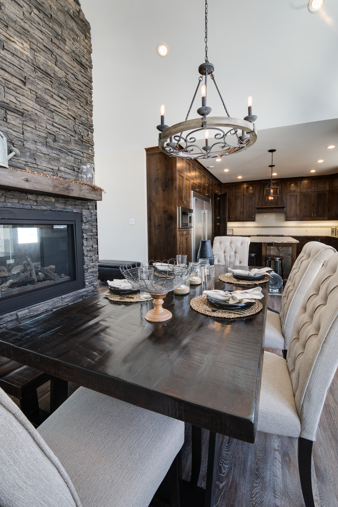 Large mountain style kitchen/dining room combo photo with beige walls, a two-sided fireplace and a stone fireplace