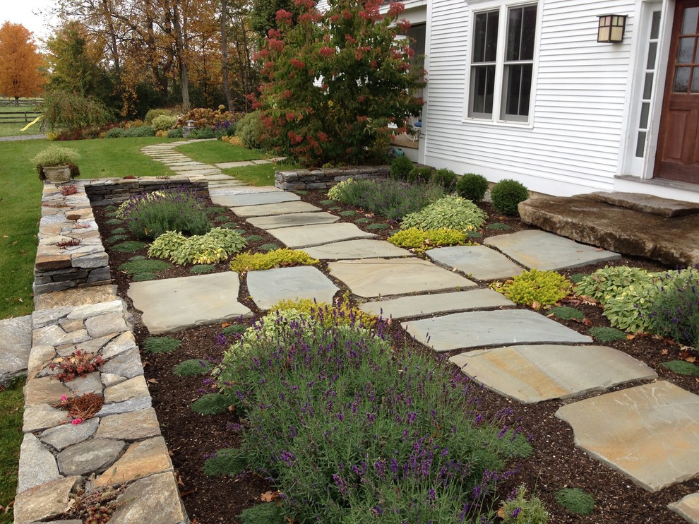 Photo of a large country backyard full sun formal garden in Burlington with a retaining wall and natural stone pavers.