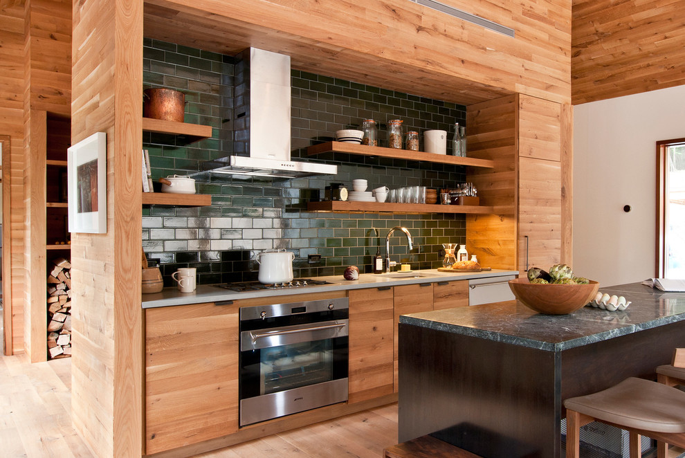 Inspiration for a mid-sized contemporary galley kitchen in Other with medium wood cabinets, light hardwood floors, with island, an undermount sink, open cabinets, green splashback, subway tile splashback and stainless steel appliances.