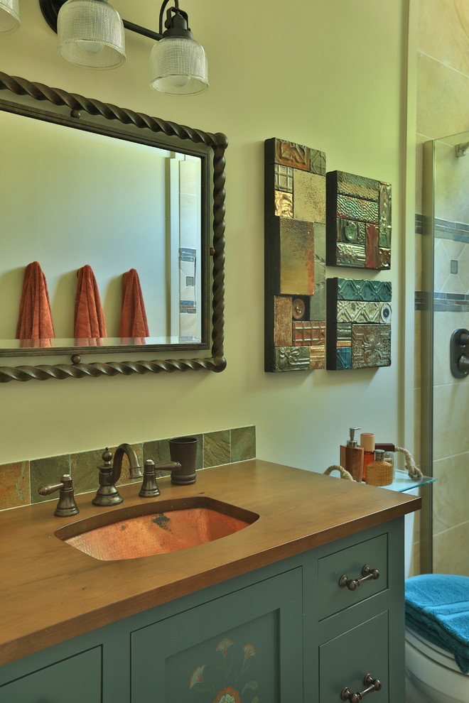 This is an example of a small beach style master bathroom in Grand Rapids with furniture-like cabinets, blue cabinets, a one-piece toilet, multi-coloured tile, stone tile, beige walls, slate floors, an undermount sink and wood benchtops.