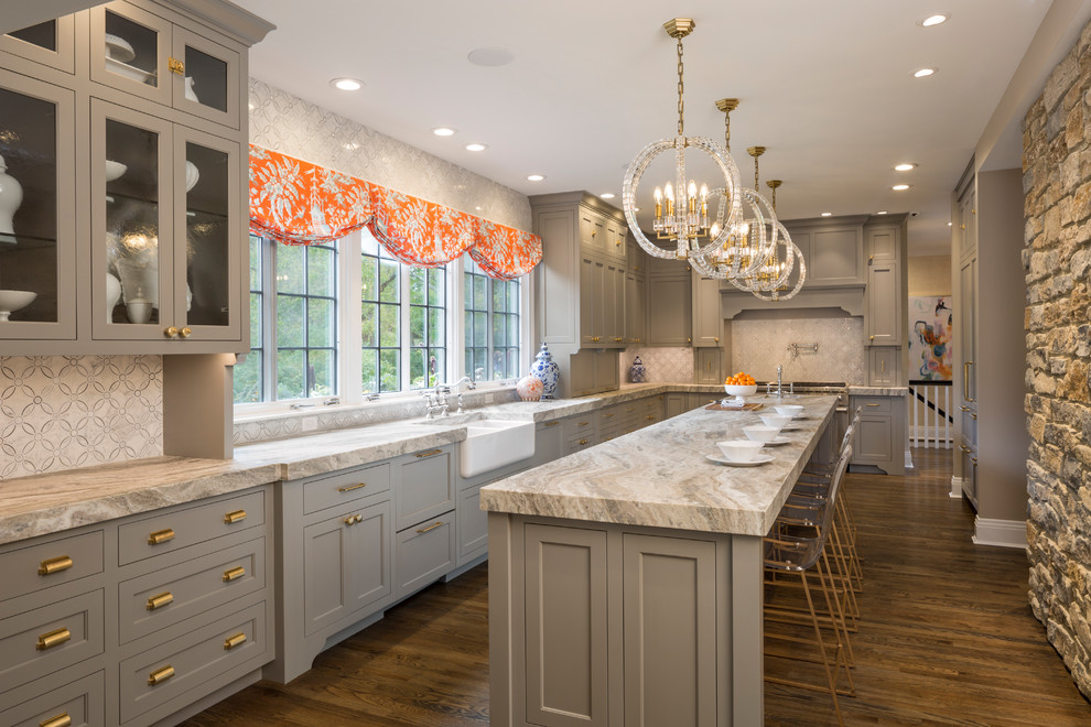 Design ideas for a traditional l-shaped separate kitchen in Cincinnati with recessed-panel cabinets, stainless steel appliances, a farmhouse sink, grey cabinets, white splashback, mosaic tile splashback, dark hardwood floors, with island, brown floor and grey benchtop.