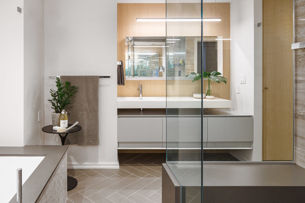 Inspiration for a large modern master bathroom in Ottawa with flat-panel cabinets, grey cabinets, a freestanding tub, a curbless shower, a wall-mount toilet, gray tile, white walls and an integrated sink.