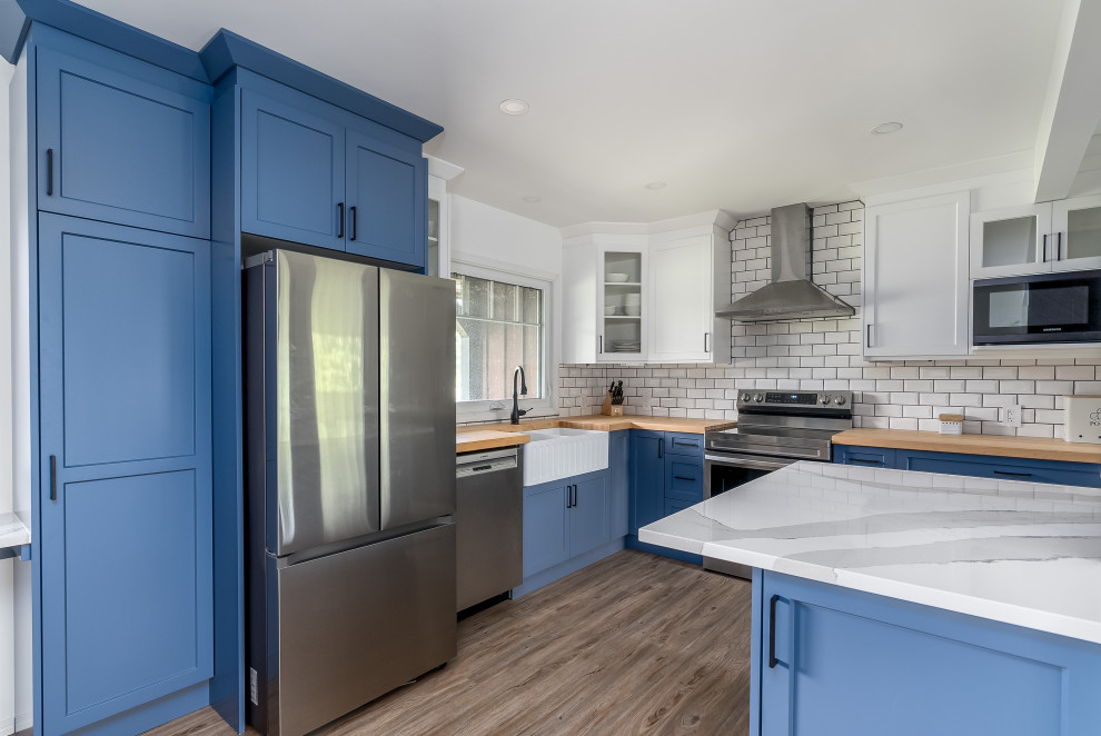 Transitional kitchen photo in Edmonton with shaker cabinets, blue cabinets, quartzite countertops, subway tile backsplash, stainless steel appliances, an island and white countertops