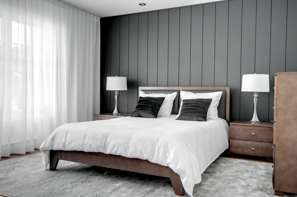 Inspiration for a mid-sized contemporary master bedroom in Montreal with black walls, medium hardwood floors and planked wall panelling.