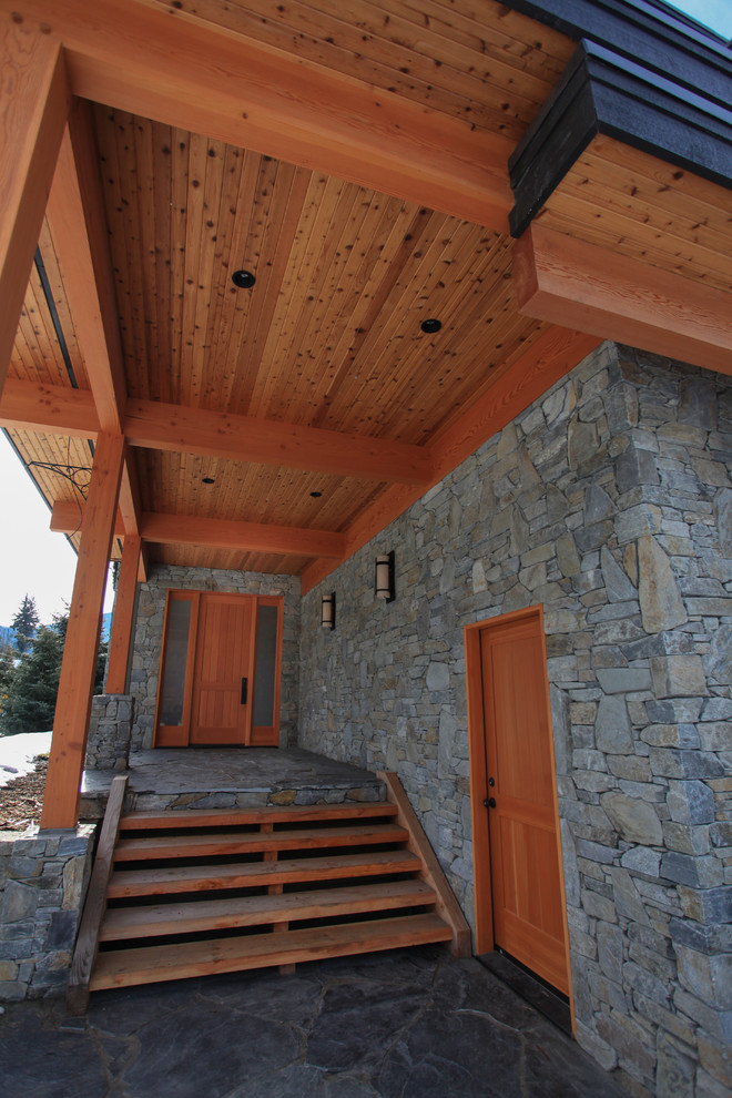 This is an example of a large transitional two-storey grey exterior in Vancouver with stone veneer and a flat roof.