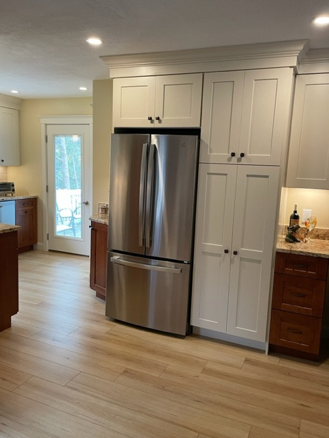 Large transitional l-shaped light wood floor and brown floor eat-in kitchen photo in Boston with no island, an undermount sink, shaker cabinets, white cabinets, granite countertops, white backsplash, stainless steel appliances, brown countertops and stone tile backsplash