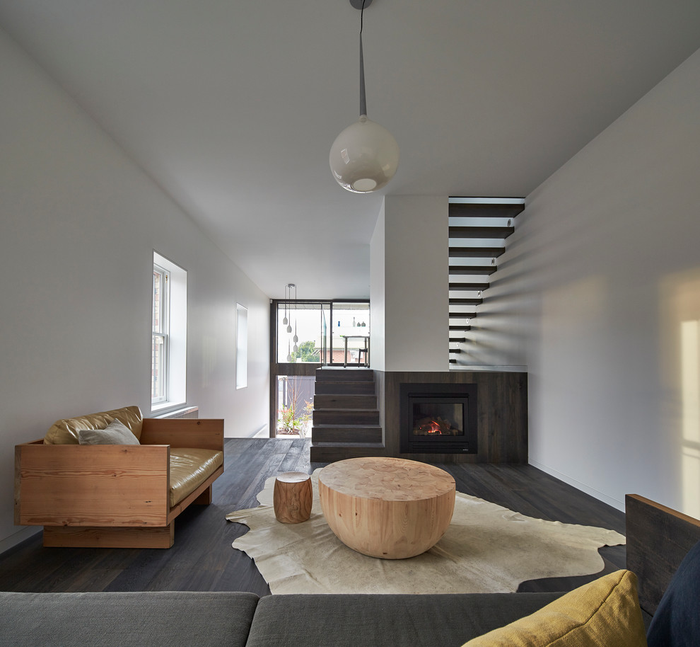 Inspiration for a contemporary open concept living room in Melbourne with white walls, dark hardwood floors, a standard fireplace and a wood fireplace surround.