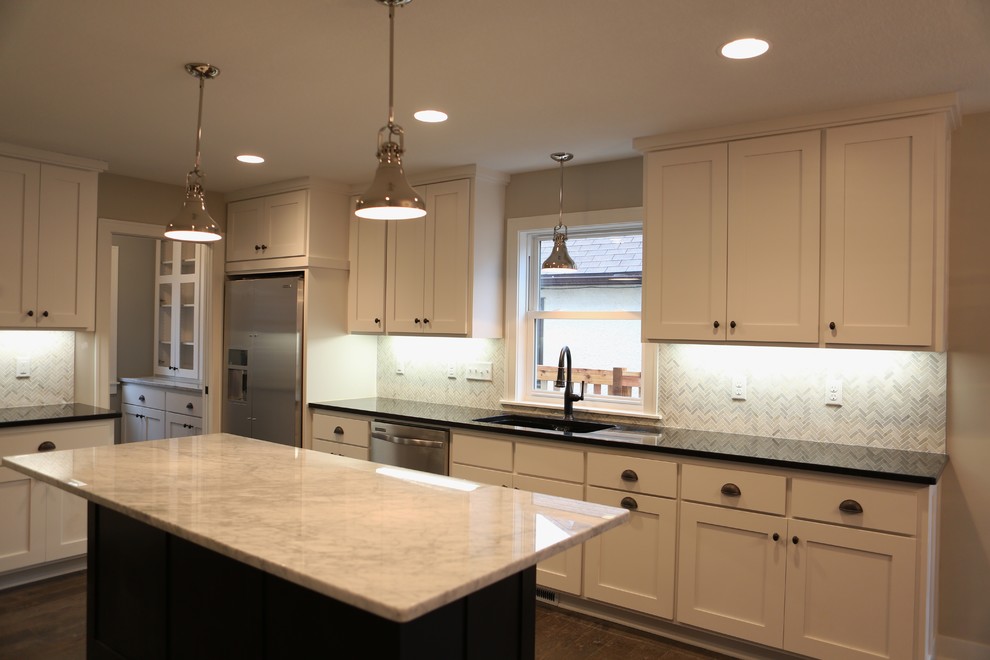 Large transitional l-shaped dark wood floor and brown floor open concept kitchen photo in Minneapolis with an undermount sink, shaker cabinets, white cabinets, quartzite countertops, white backsplash, stone slab backsplash, stainless steel appliances, an island and white countertops