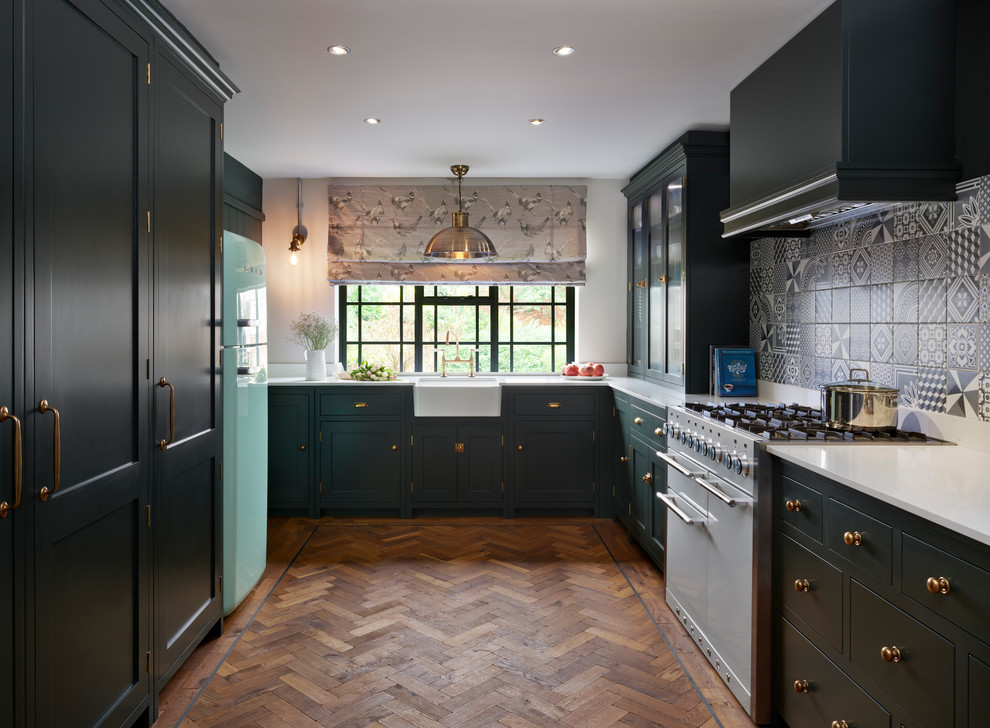 Design ideas for a mid-sized transitional u-shaped separate kitchen in Essex with a farmhouse sink, green cabinets, quartz benchtops, grey splashback, ceramic splashback, white appliances, no island, flat-panel cabinets, dark hardwood floors and white benchtop.