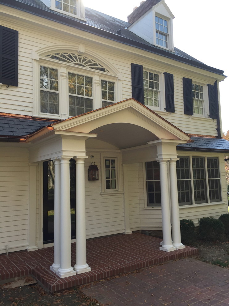 Mid-sized traditional front yard verandah in Louisville with brick pavers and a roof extension.