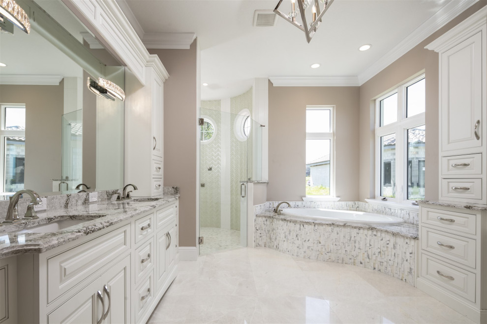 This is an example of a large contemporary master bathroom in Orlando with furniture-like cabinets, beige cabinets, a hot tub, a double shower, green tile, brown walls, travertine floors, an undermount sink, granite benchtops, beige floor, a hinged shower door, beige benchtops, an enclosed toilet, a double vanity and a built-in vanity.