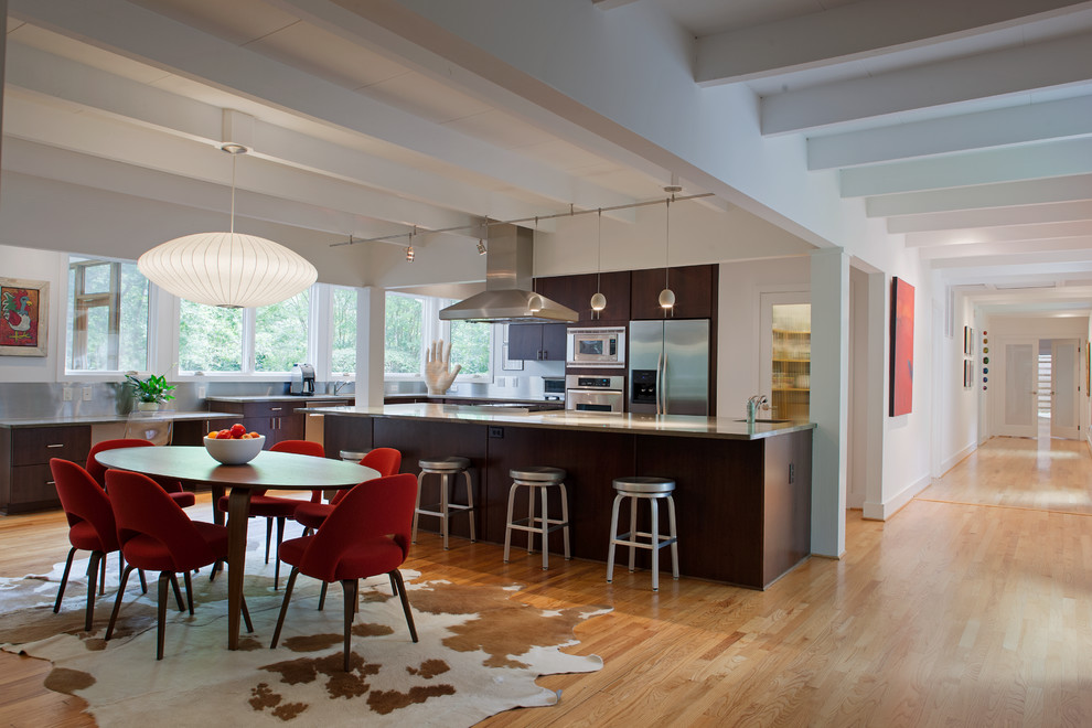 Photo of a contemporary l-shaped eat-in kitchen in Raleigh with flat-panel cabinets, dark wood cabinets, stainless steel appliances, light hardwood floors and with island.