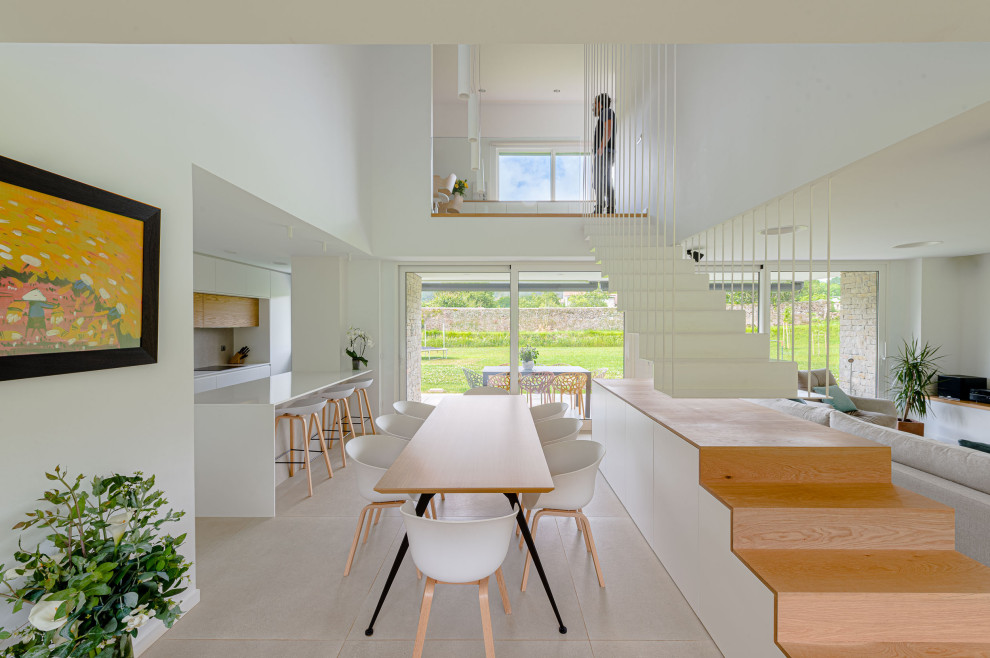 Foto di una sala da pranzo aperta verso il soggiorno minimal con pareti bianche, pavimento con piastrelle in ceramica e pavimento beige