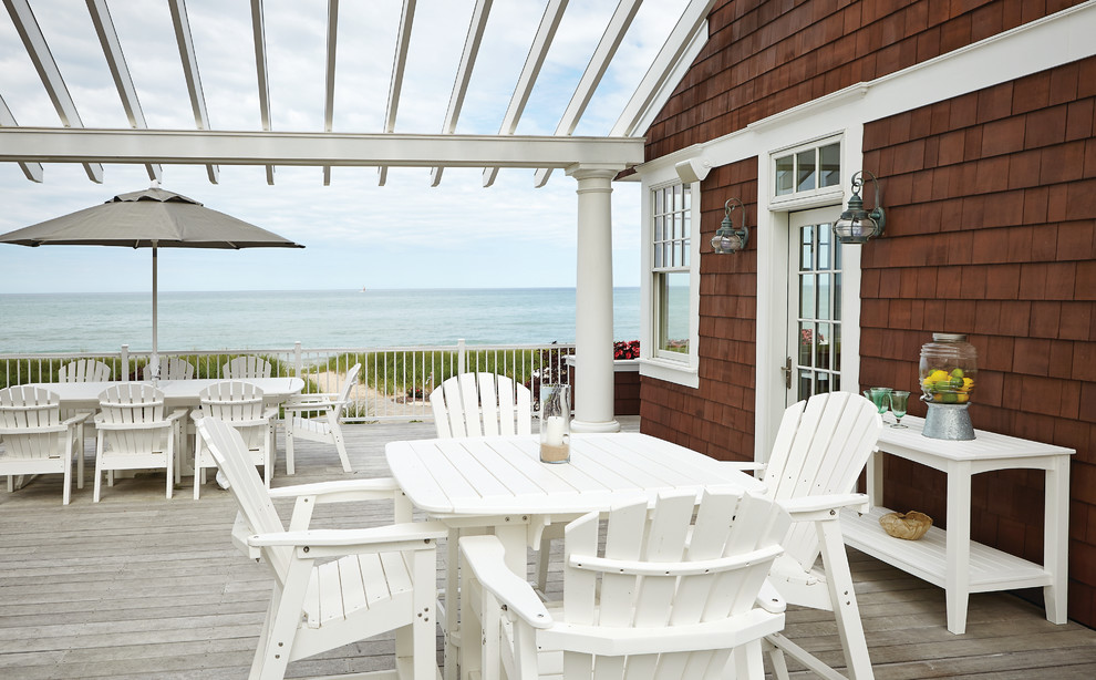 Design ideas for a beach style backyard deck in Grand Rapids with a pergola.