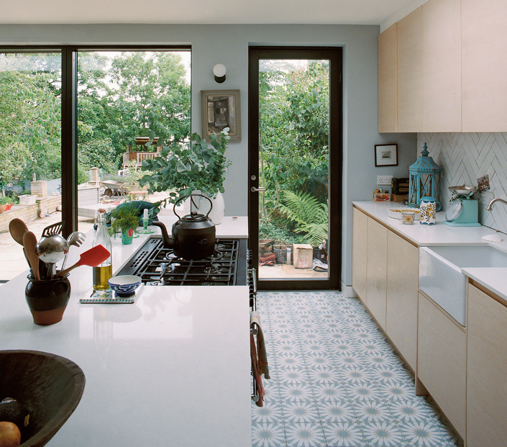 Exempel på ett mellanstort vit vitt kök och matrum, med en integrerad diskho, släta luckor, skåp i ljust trä, bänkskiva i kvartsit, vitt stänkskydd, stänkskydd i keramik, svarta vitvaror, klinkergolv i keramik och en köksö