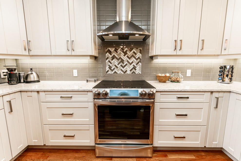 Large transitional u-shaped medium tone wood floor eat-in kitchen photo in Calgary with an undermount sink, shaker cabinets, white cabinets, gray backsplash, glass tile backsplash, stainless steel appliances, an island and marble countertops