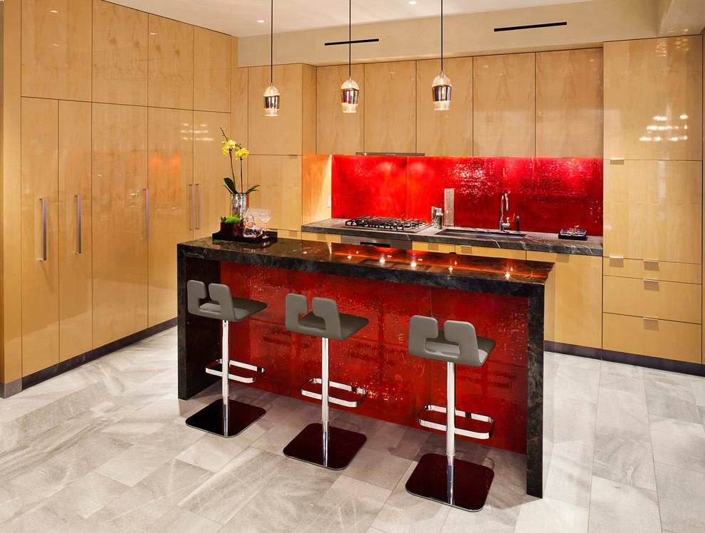This is an example of a contemporary galley eat-in kitchen in Los Angeles with an undermount sink, flat-panel cabinets, light wood cabinets, red splashback, panelled appliances, porcelain floors, with island, grey floor, black benchtop, granite benchtops and ceramic splashback.