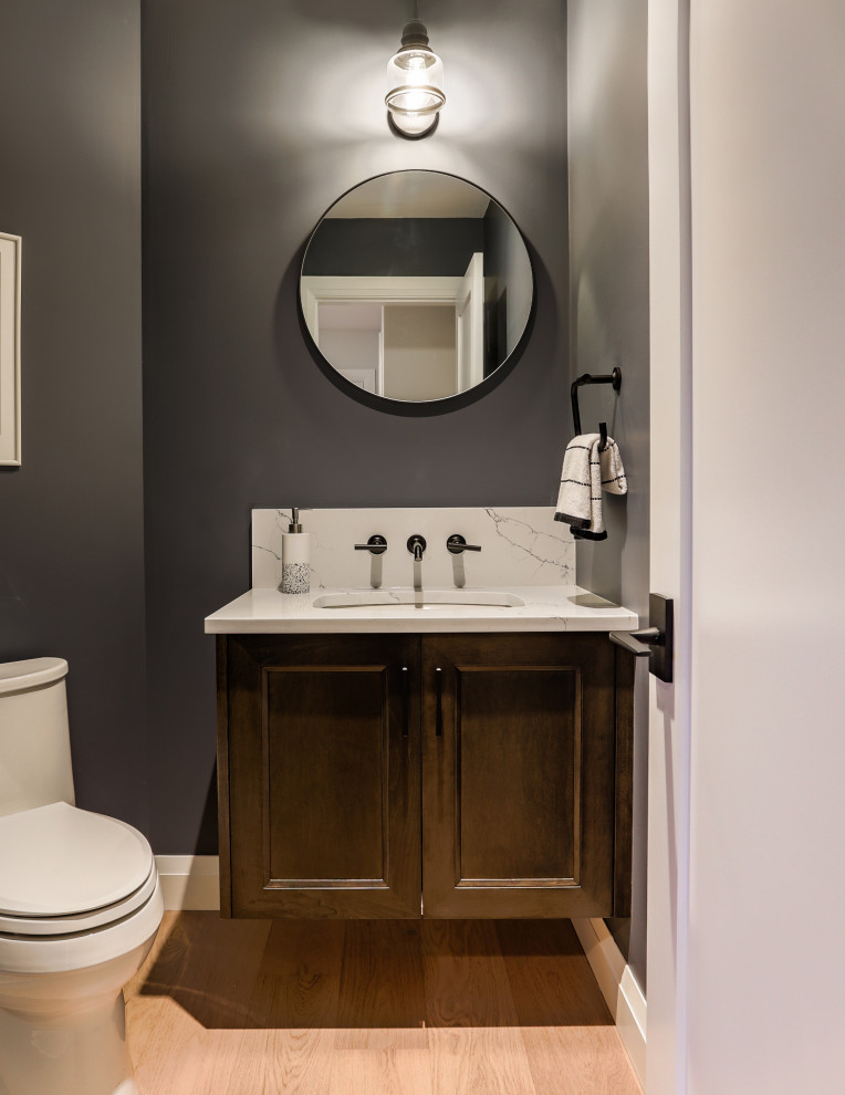 Klassisk inredning av ett litet vit vitt toalett, med luckor med infälld panel, bruna skåp, en toalettstol med hel cisternkåpa, grå väggar, ljust trägolv, ett undermonterad handfat, bänkskiva i kvarts och beiget golv