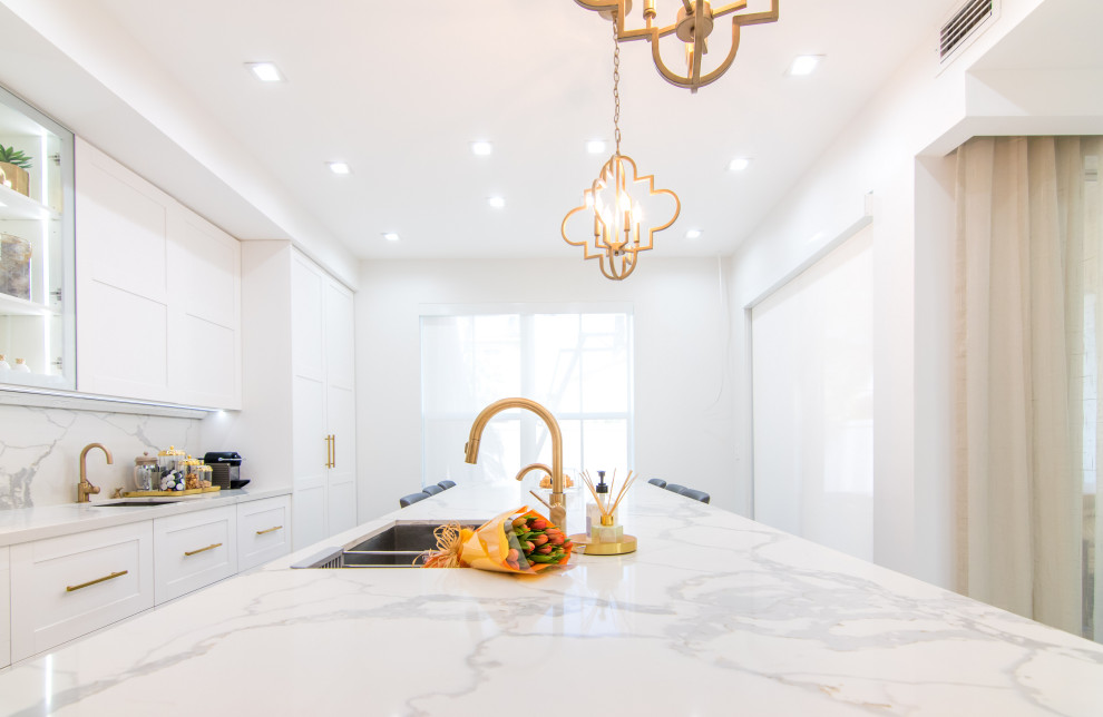 Inspiration for a large transitional l-shaped porcelain tile and white floor open concept kitchen remodel in Miami with an undermount sink, shaker cabinets, white cabinets, quartz countertops, white backsplash, porcelain backsplash, stainless steel appliances, an island and white countertops