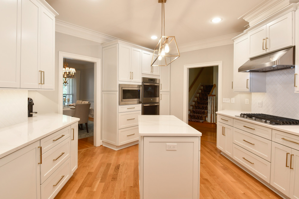 Exempel på ett mycket stort klassiskt vit vitt kök, med en nedsänkt diskho, luckor med infälld panel, vita skåp, bänkskiva i kvarts, stänkskydd i mosaik, rostfria vitvaror och en köksö